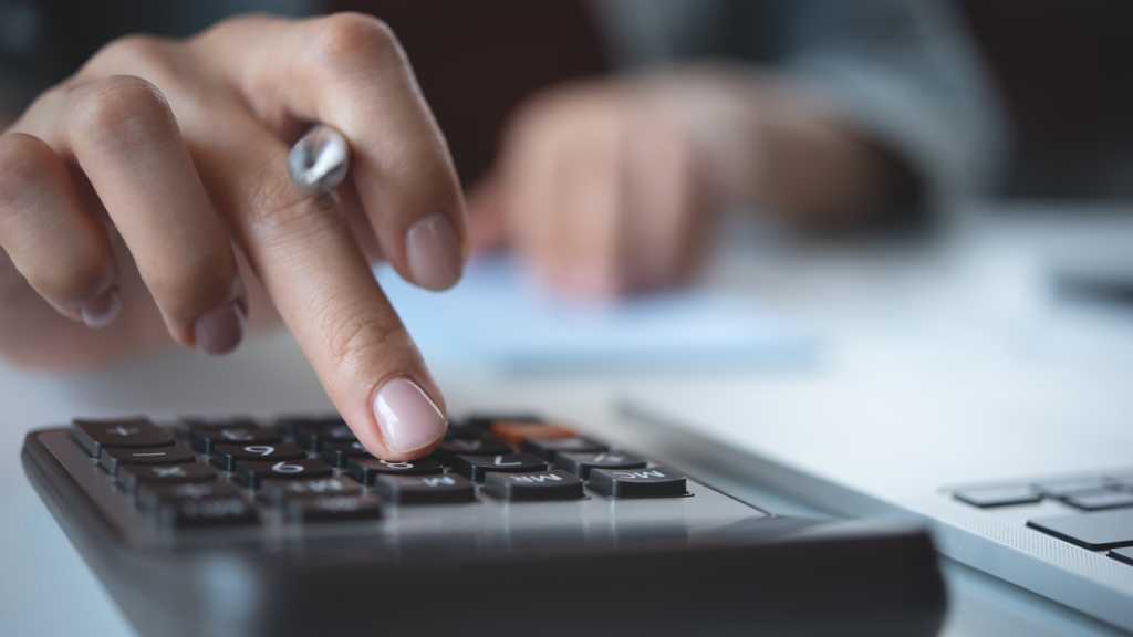 A photograph of a hand pushing a button on a calculator.